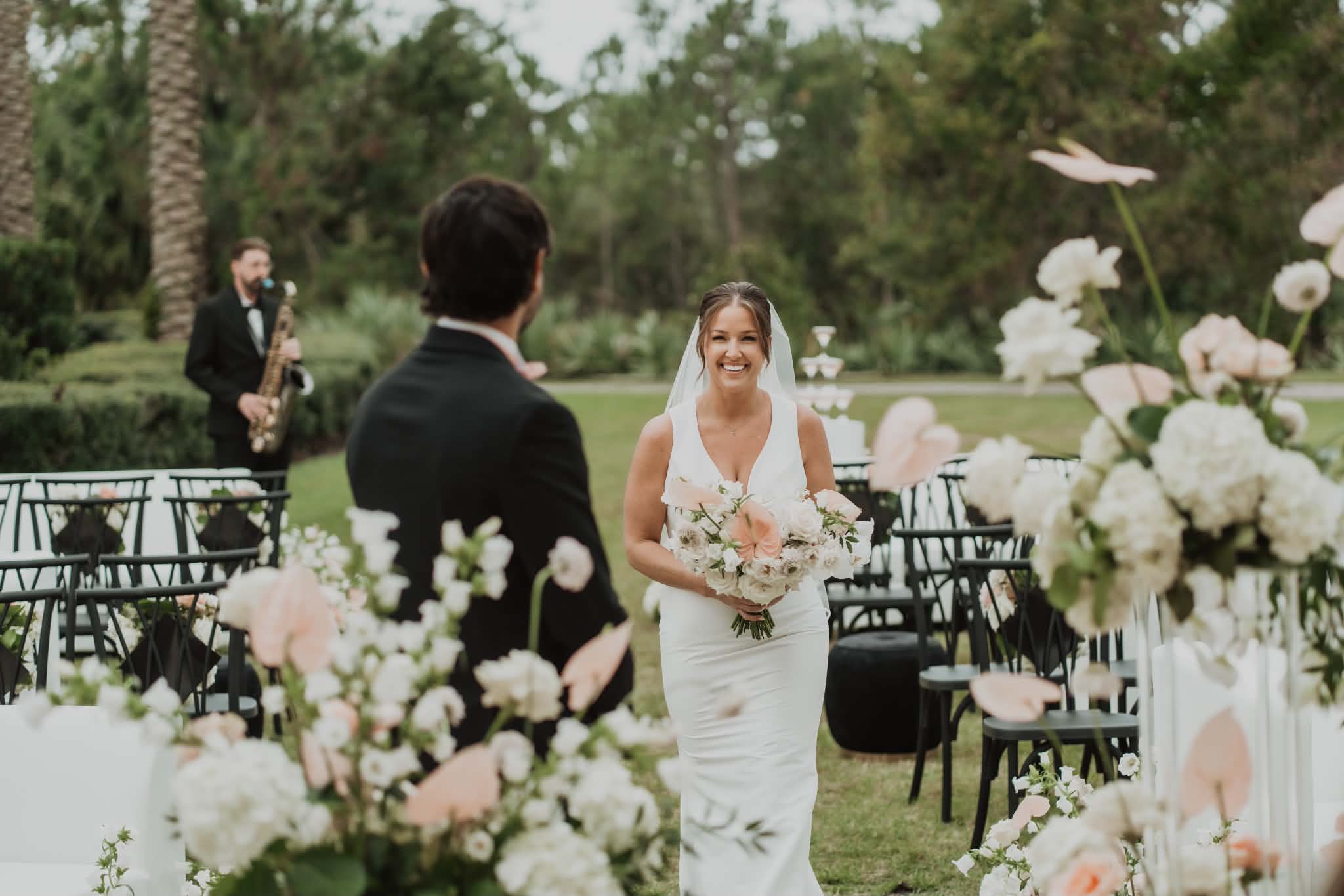 Bride walking down the aisle to her groom, romantic updo and veil in place for the ceremony