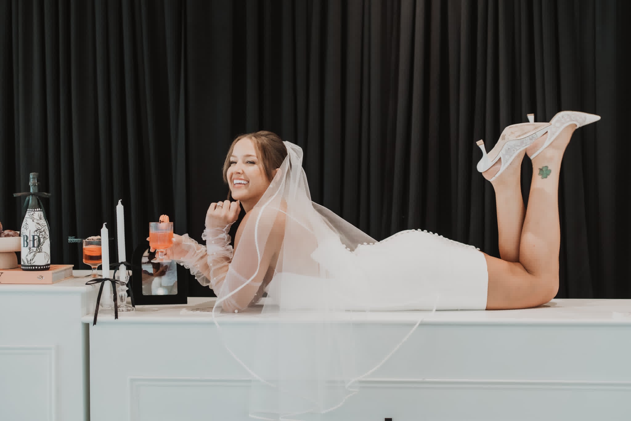 Bride laughing at the reception bar, wedding-day hair and makeup holding up through the celebration